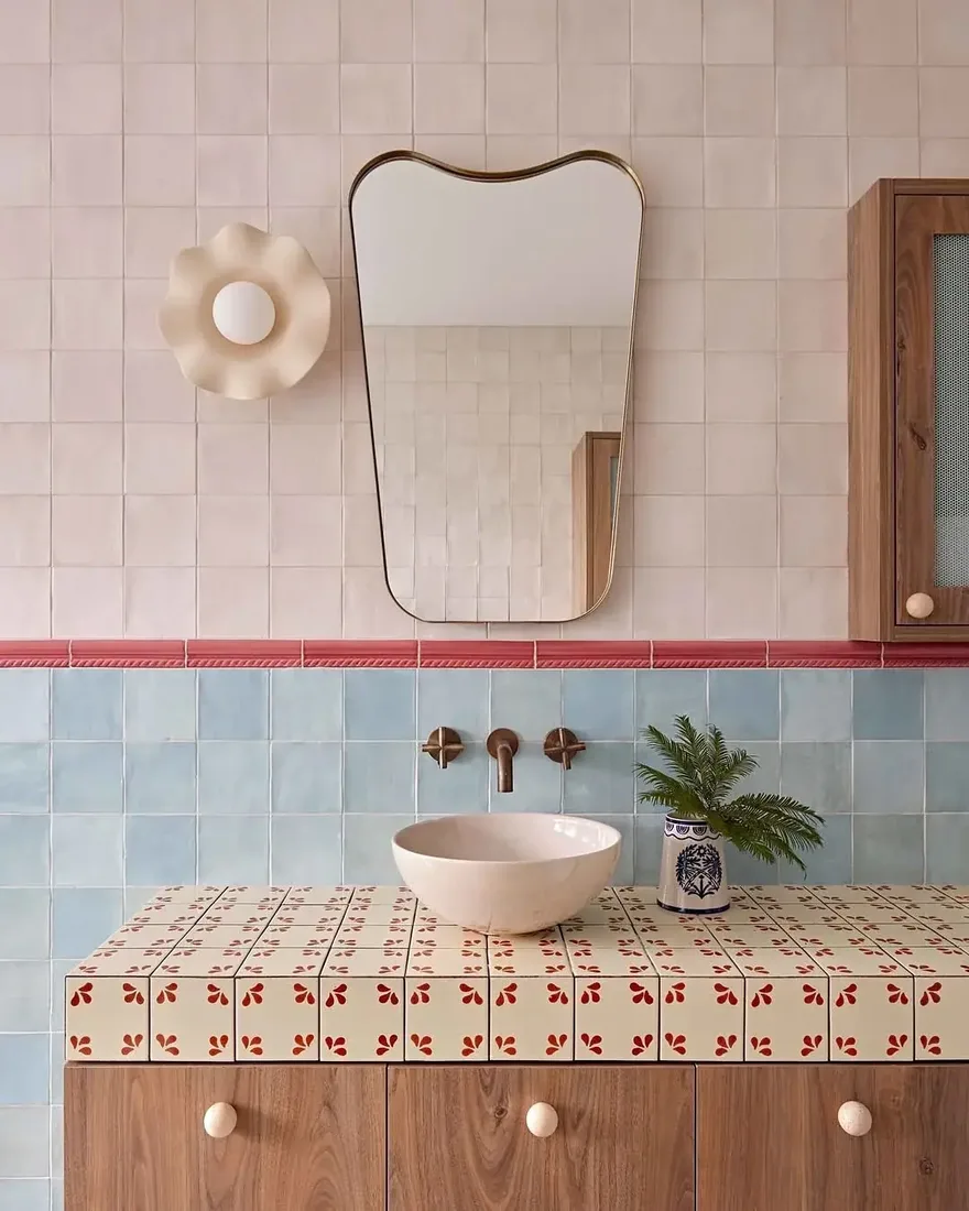 Bathroom with pink and blue zellige tiles, wooden vanity and soft lighting