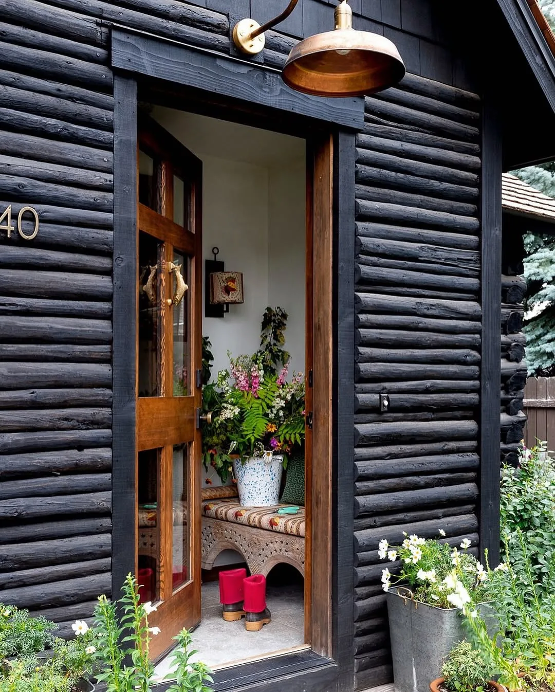 Black log cabin door with a copper lantern glowing beside it