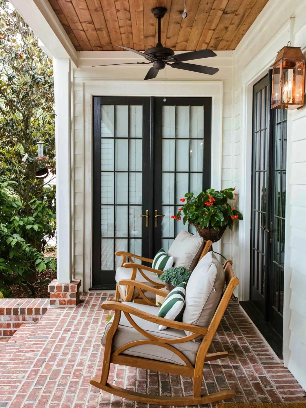 Brick porch with wood rocking chairs and black double doors