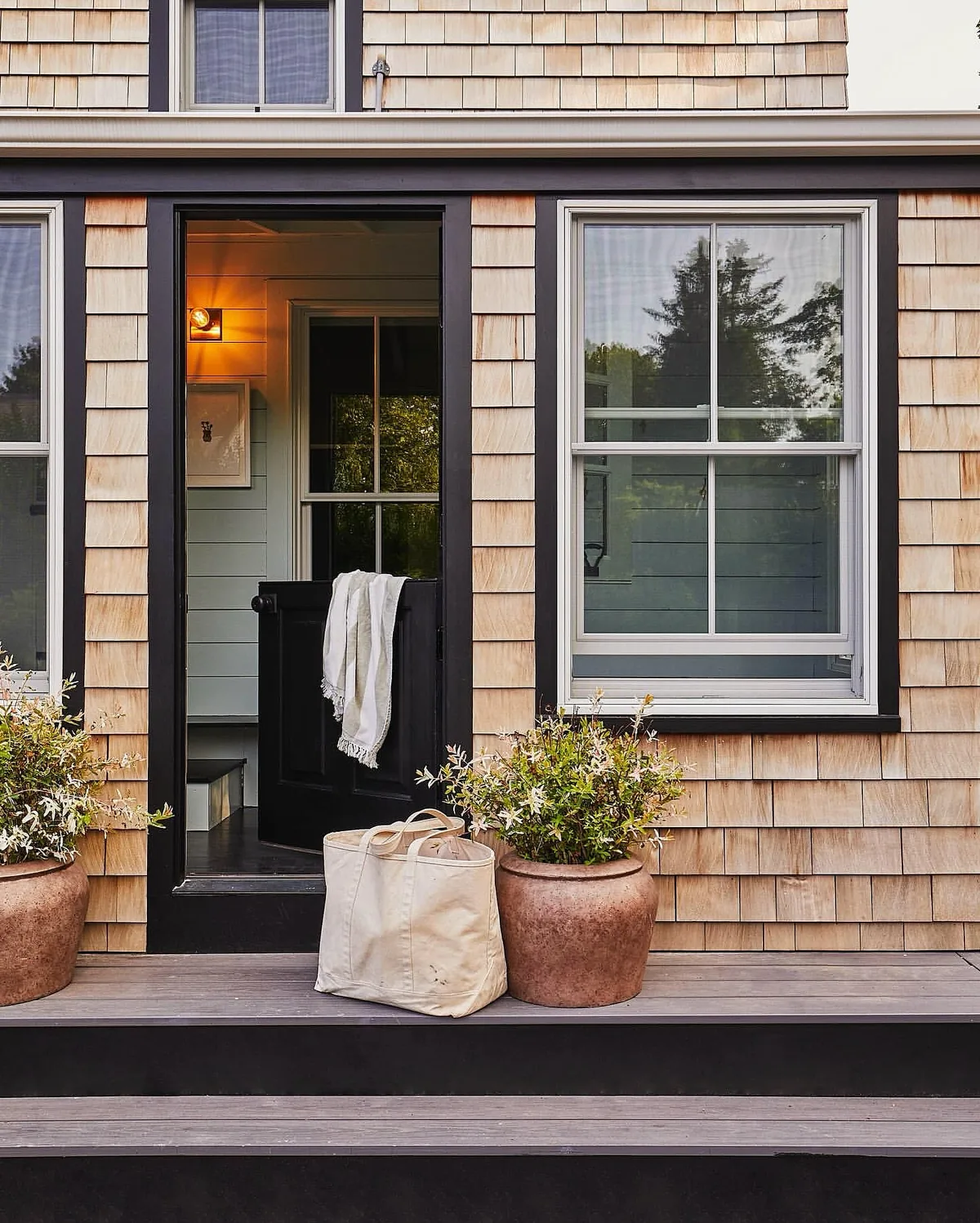 Cedar shingle entry with a black door and terracotta pots