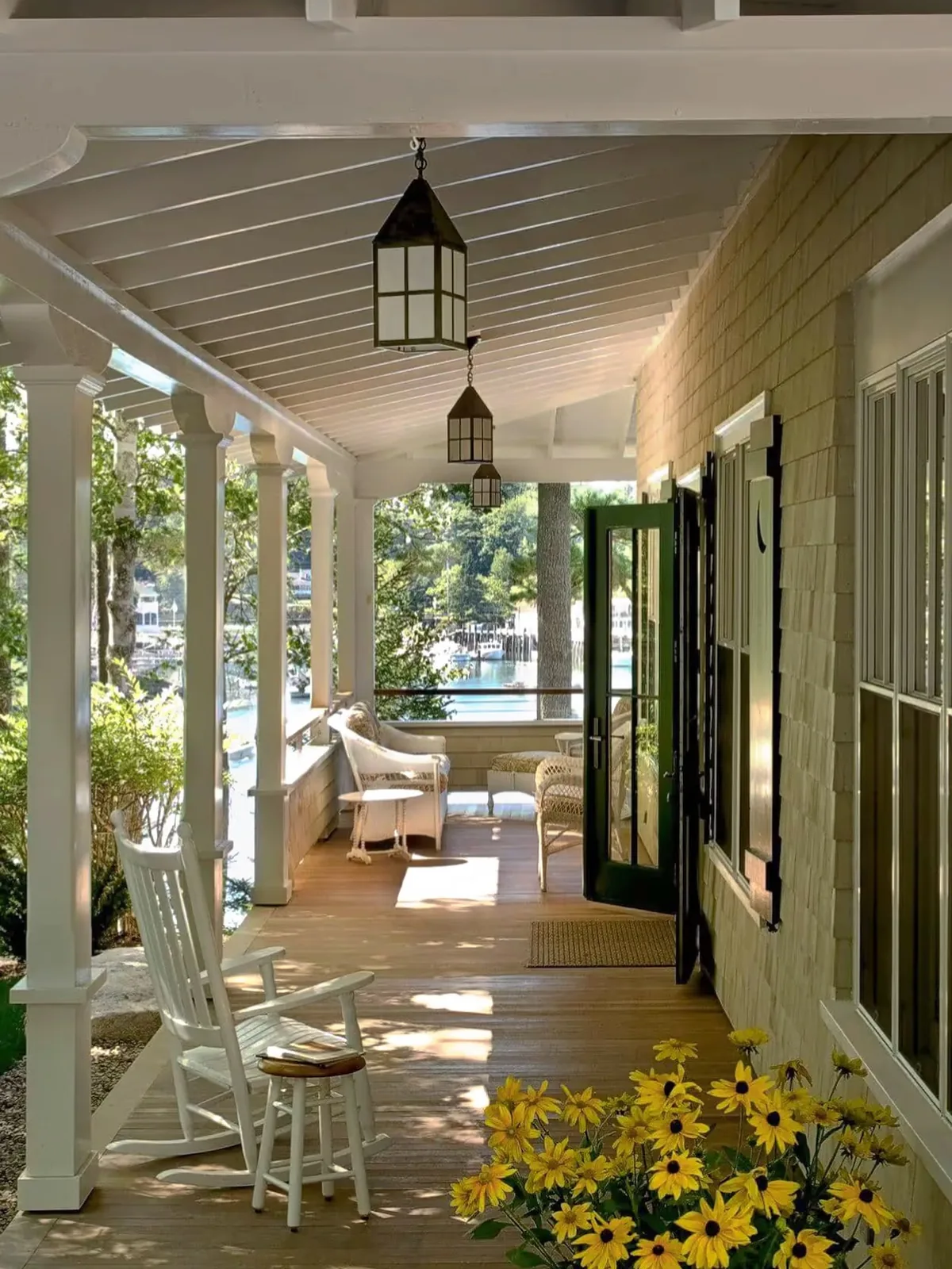 Shingle house with a wraparound porch and black-eyed Susans along the rail