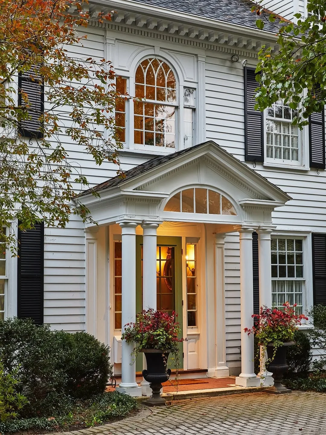 White clapboard portico with black shutters, columns and a black door