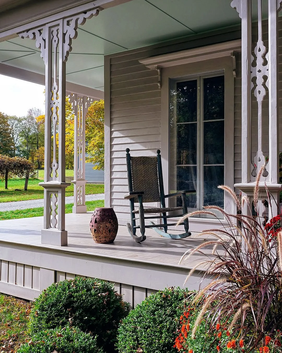 White gingerbread porch with a black rocking chair and detailed trim
