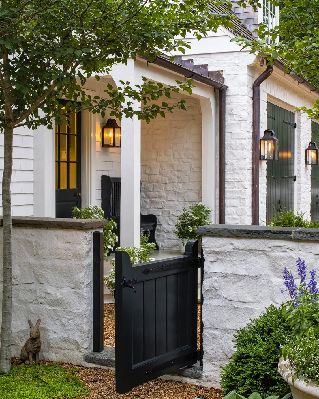 White stone entry with a black gate and twin lanterns