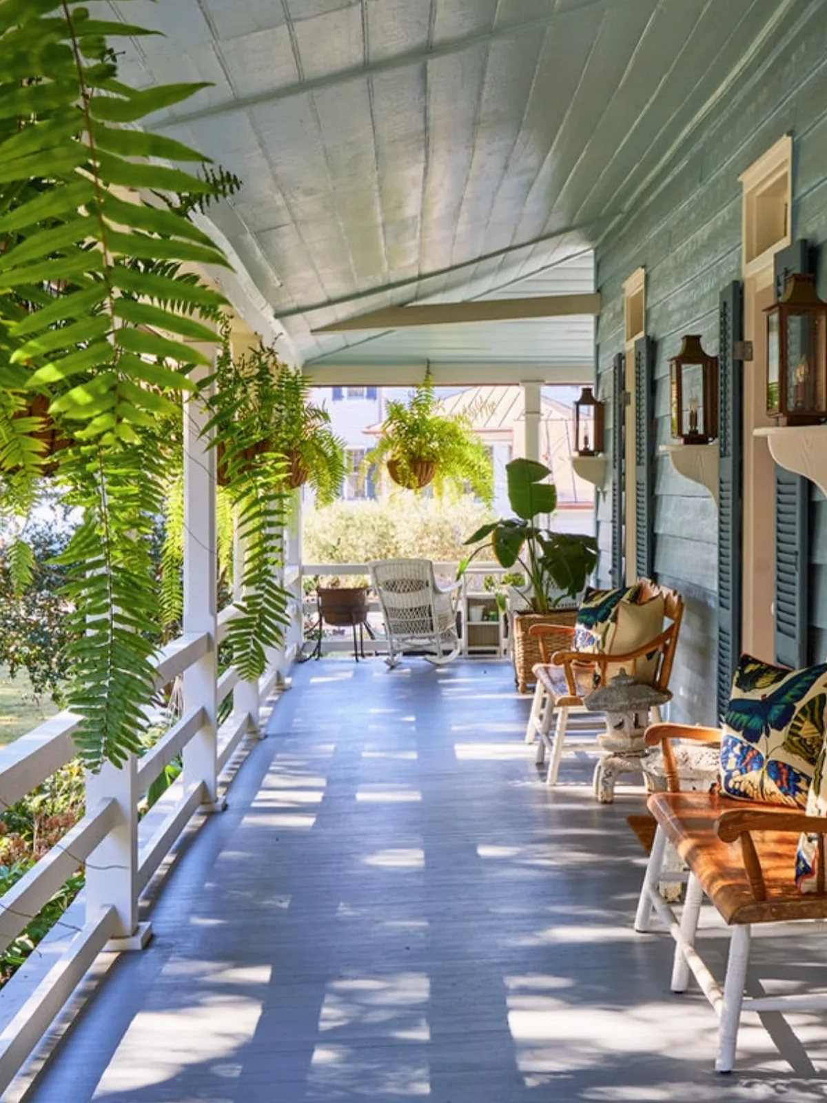 Blue painted porch floor with hanging ferns softening the entry