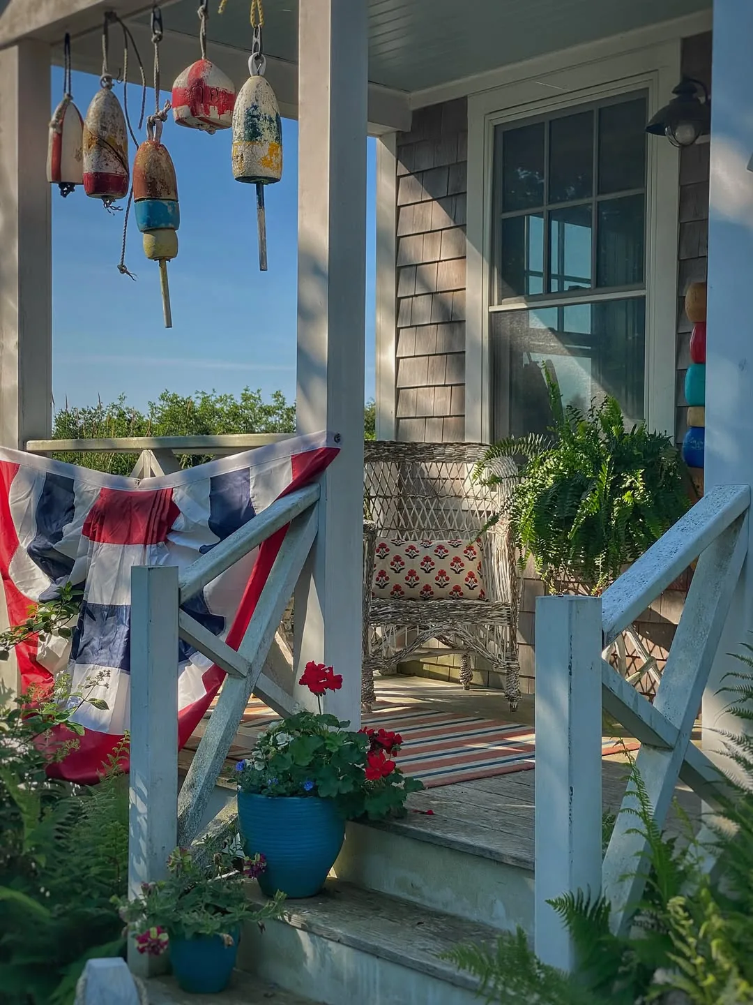 Bright coastal porch with blue bunting, lobster buoys and wicker seating