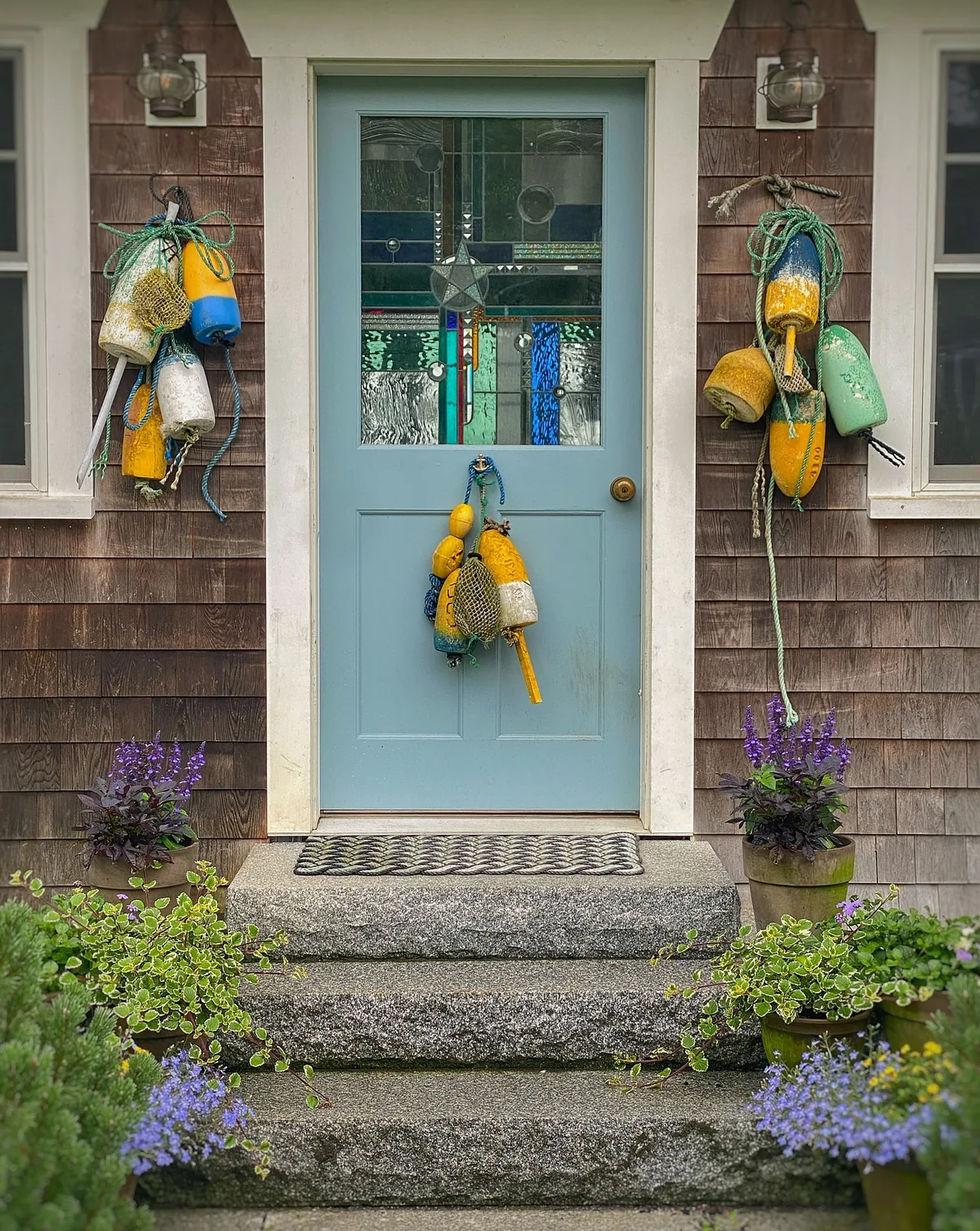Light blue door on a shingle cottage with buoys by the entry
