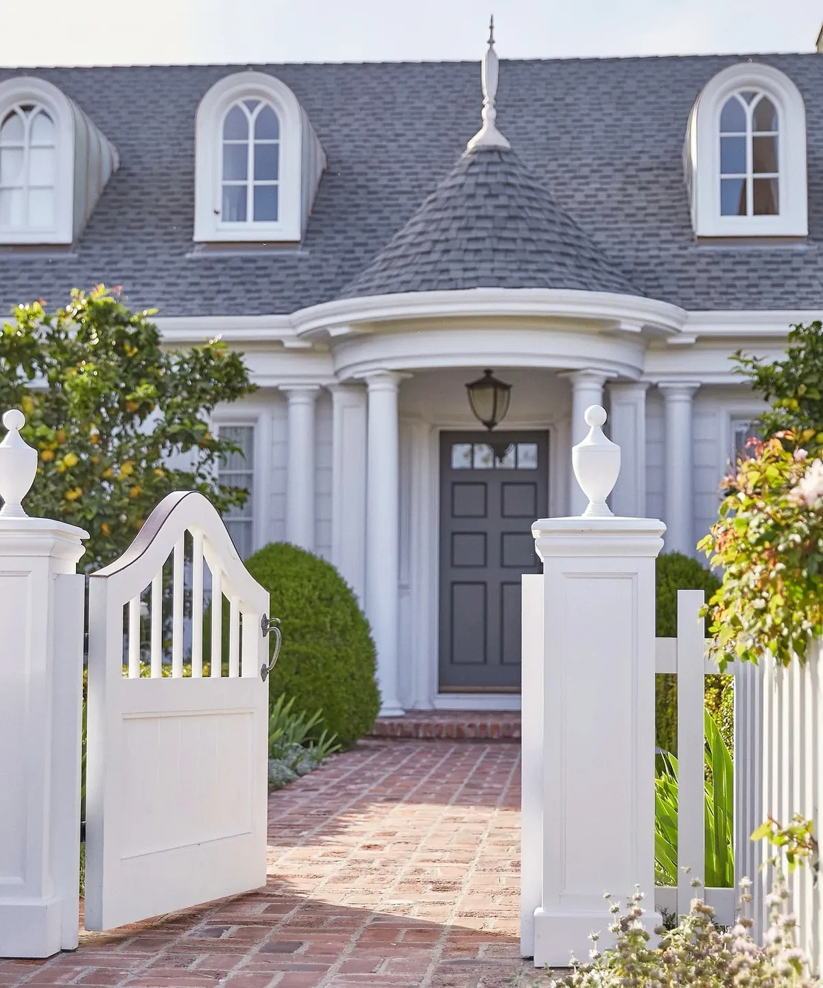 Navy front door with white columns and a brick walkway leading in