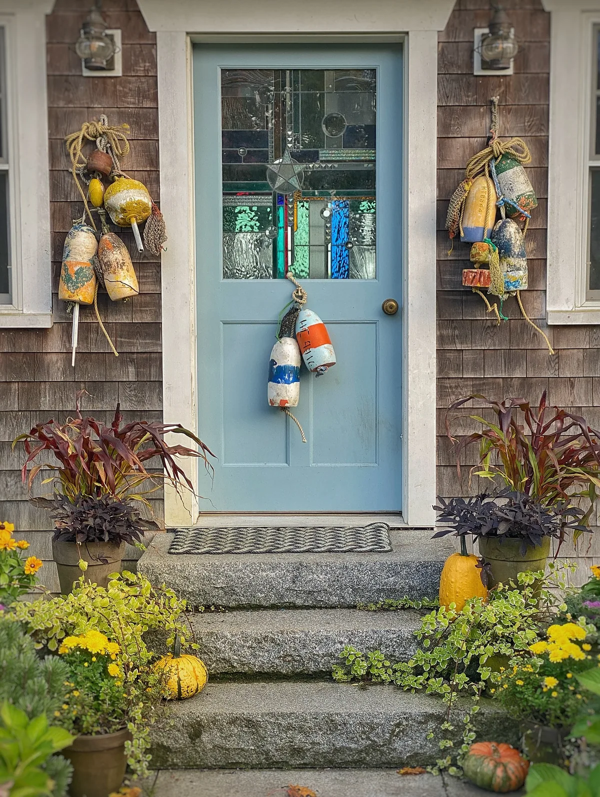 Pale blue door with granite steps and pumpkins marking the season