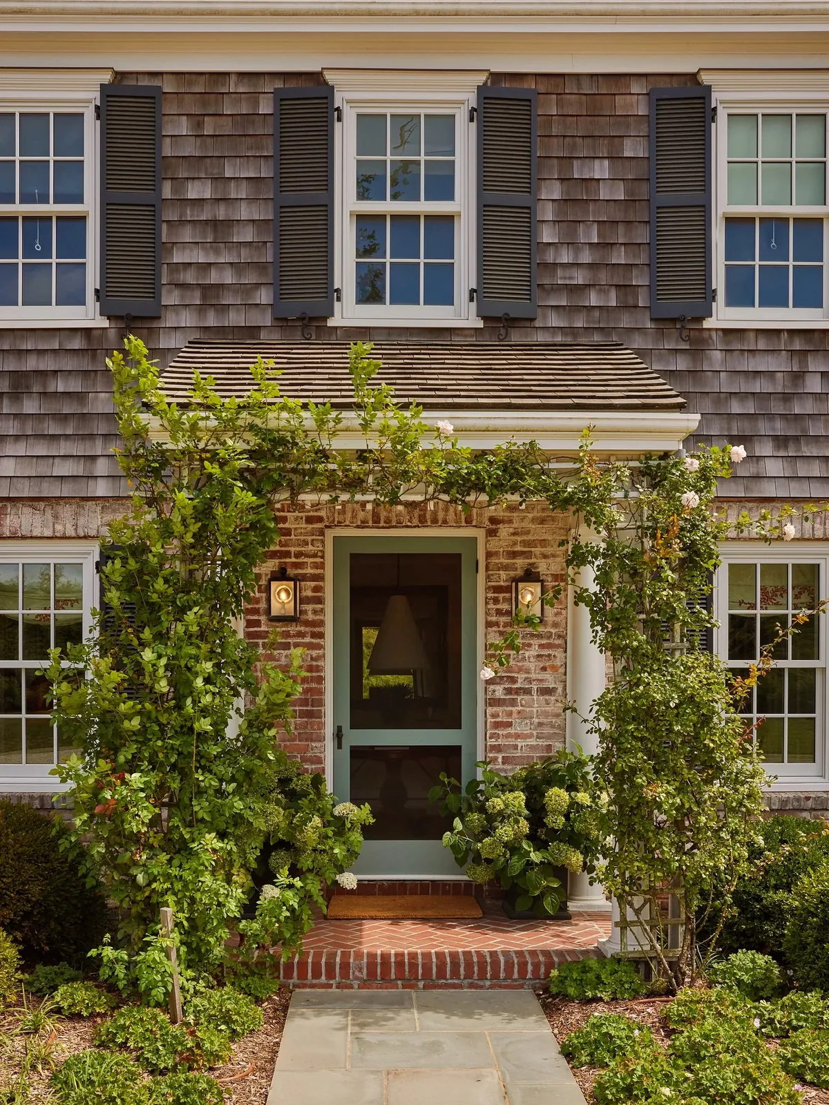 Cedar shake house with a brick entry softened by climbing vines