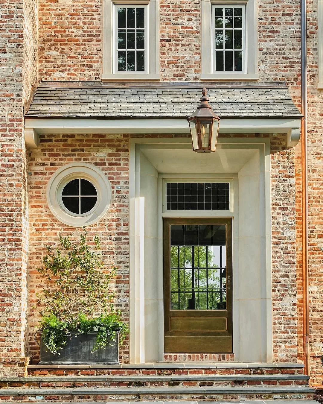 Reclaimed brick entry with a glass door and a lantern beside