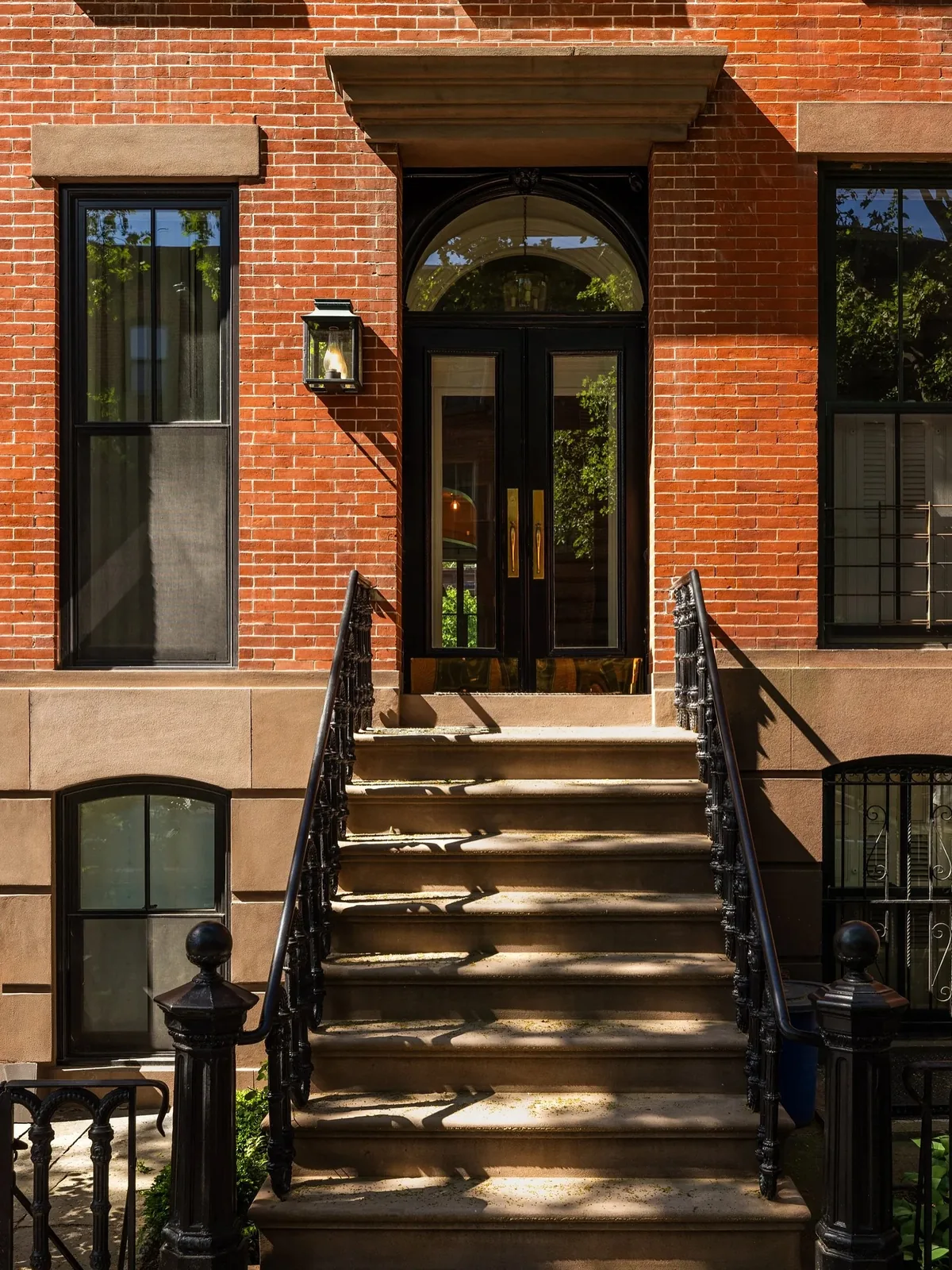 Red brick brownstone stoop with an iron railing