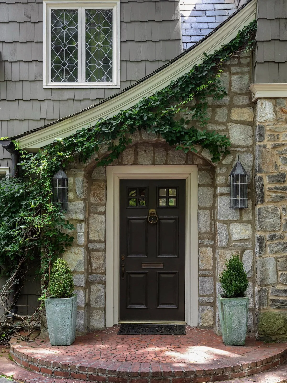 Stone cottage with a dark door, ivy and a brick step