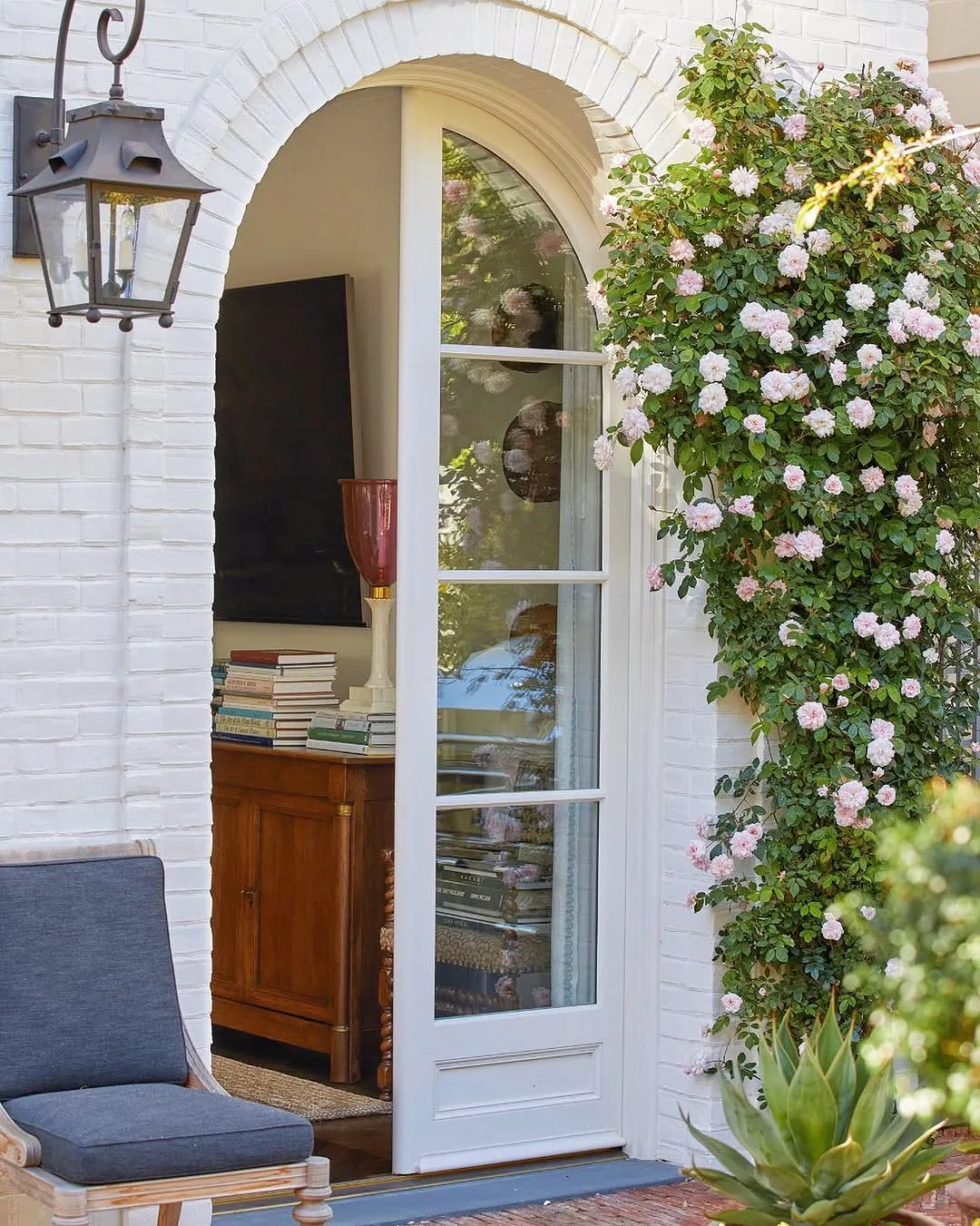 White brick arch with climbing roses framing the door