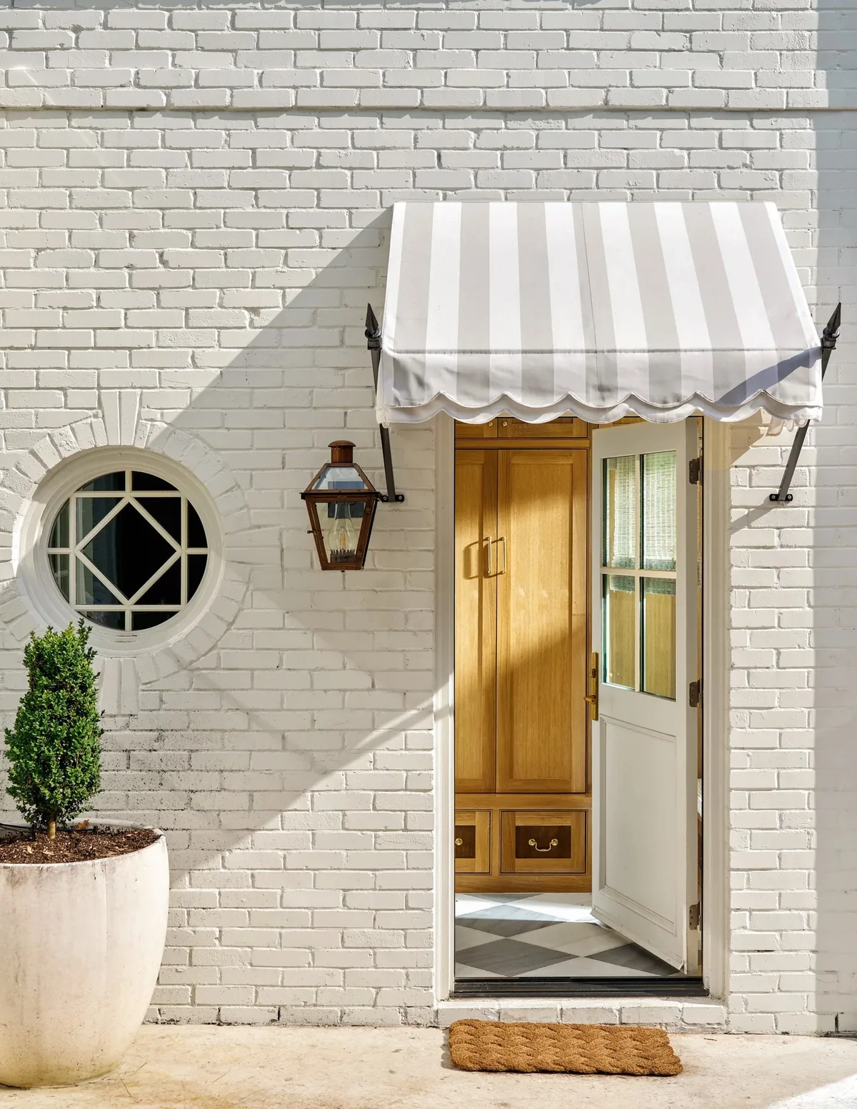 White brick house with a striped awning and a Dutch door