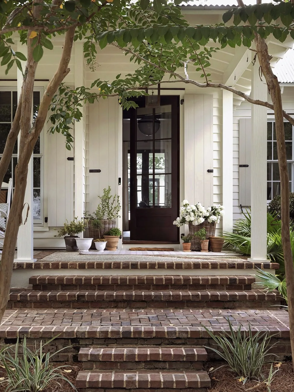 White farmhouse front porch with classic columns and simple seating