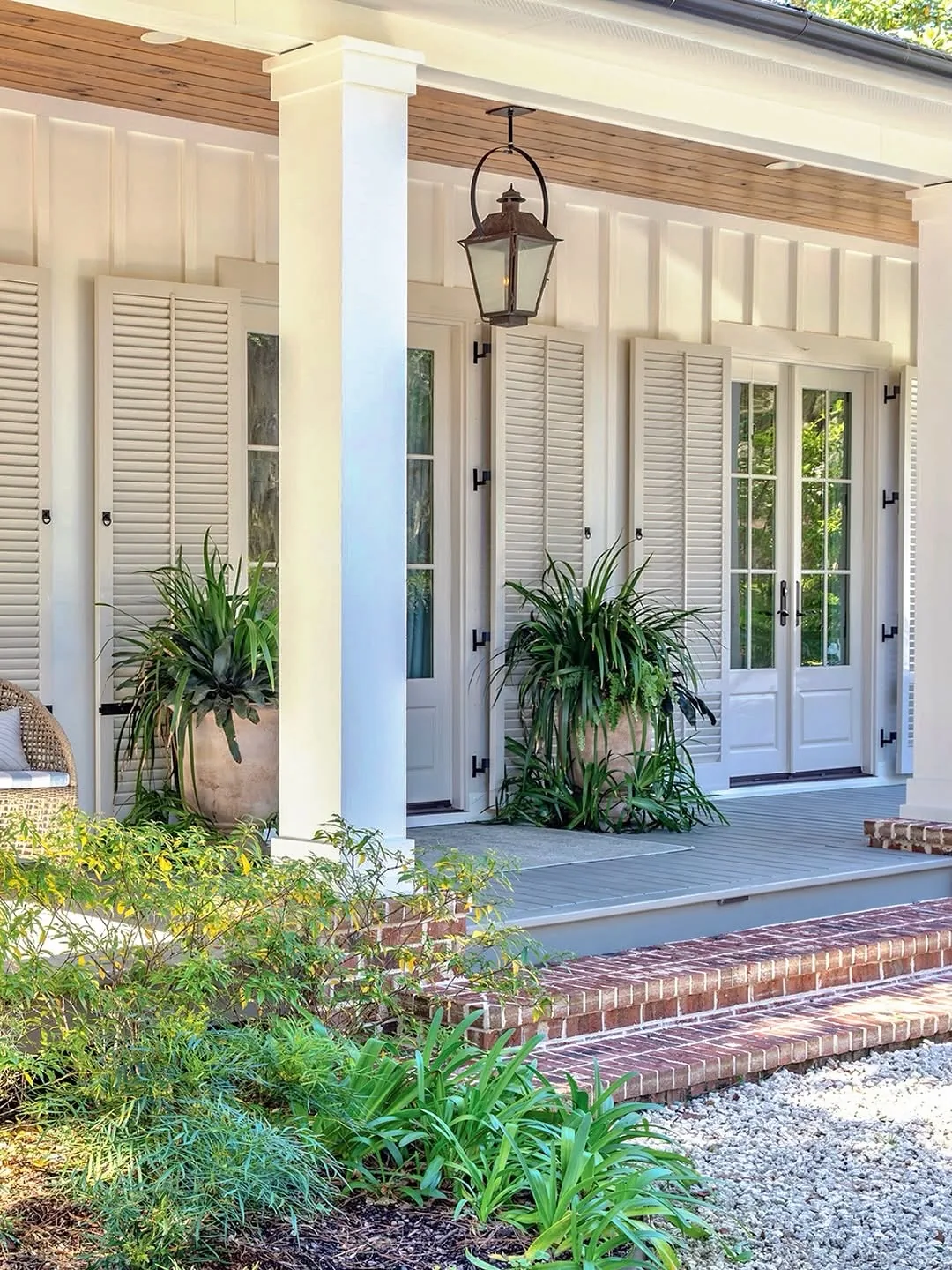 White farmhouse front porch styled with layered seating and textiles