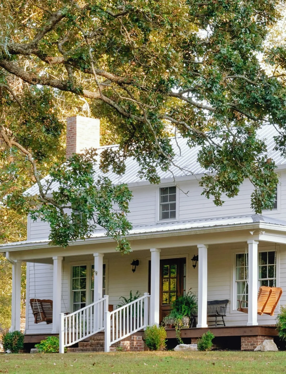 White farmhouse front porch with rocking chairs facing the yard