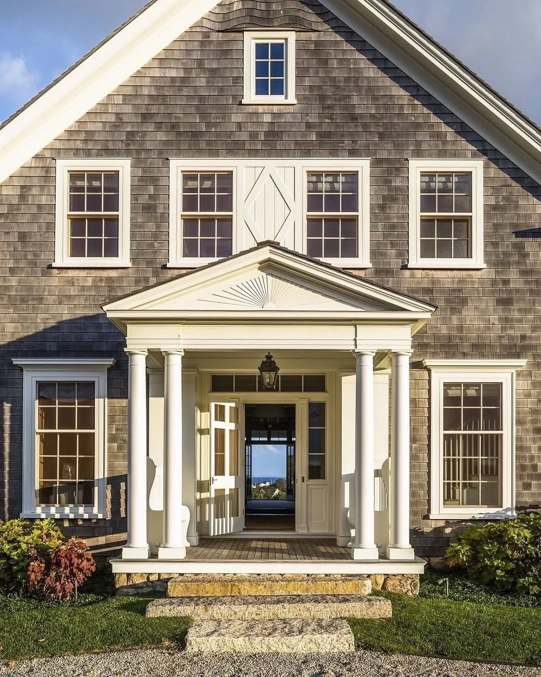 Brown shingle house with a columned portico sheltering the entry