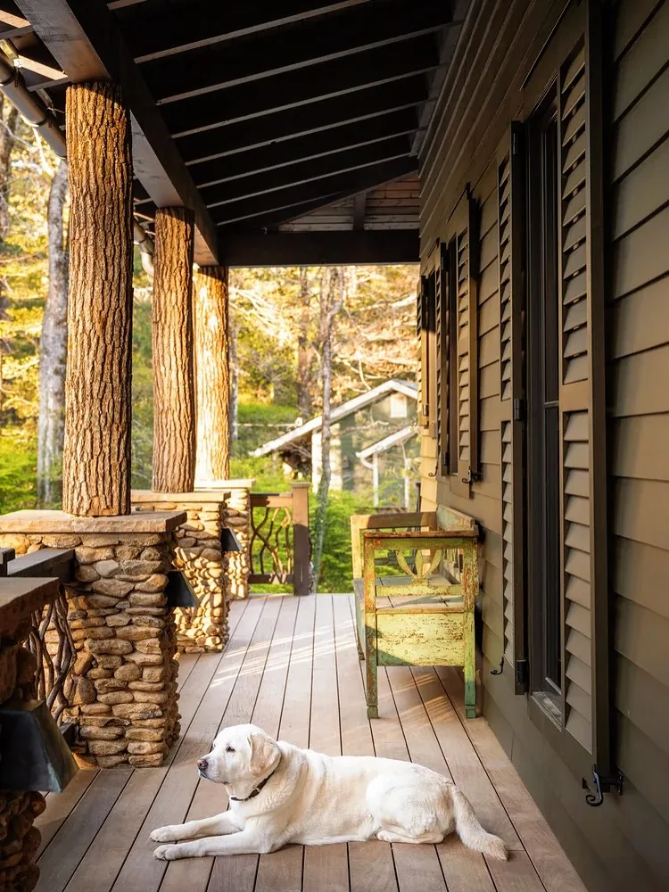 Log column porch with a stone base and a wood railing