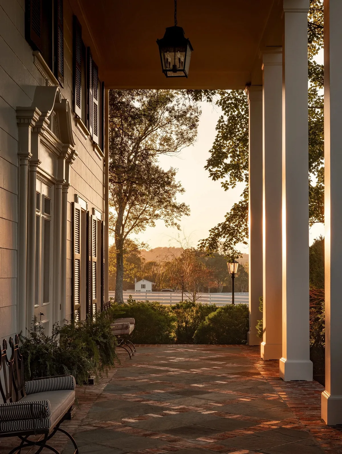 Long columned porch with a brick floor glowing at sunset