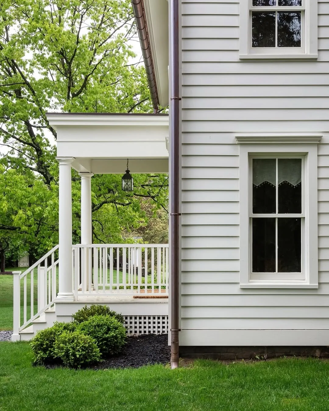 White clapboard porch with columns and a simple railing