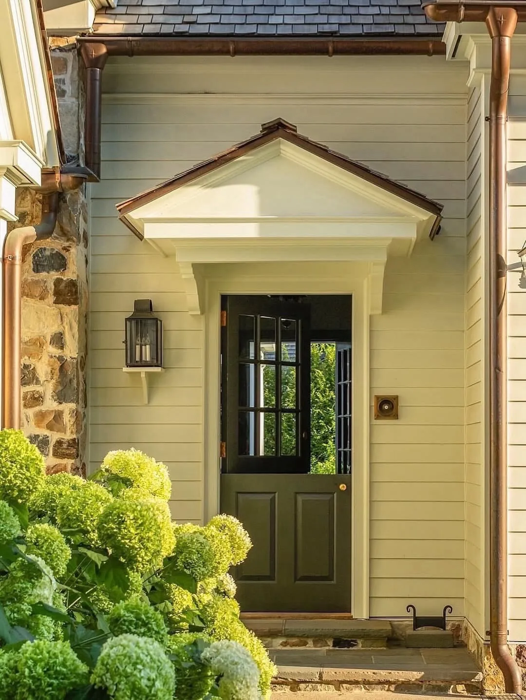 Cream clapboard house with an olive green door under a pediment
