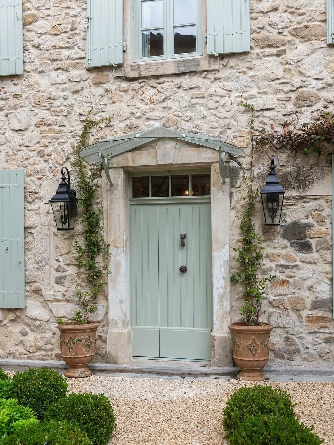 Fieldstone cottage with a mint green door in a garden setting