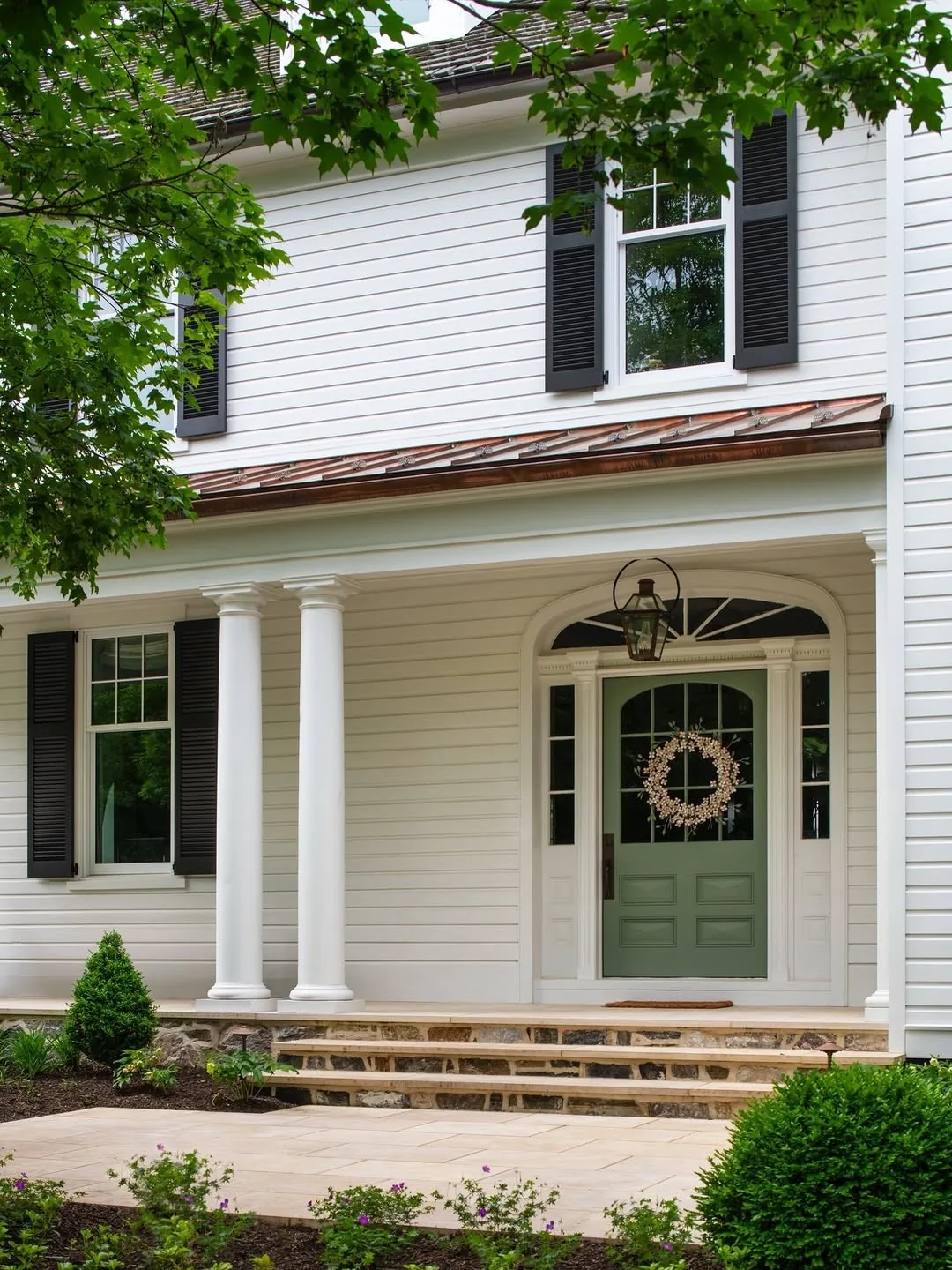 Green front door with white columns under a copper roof