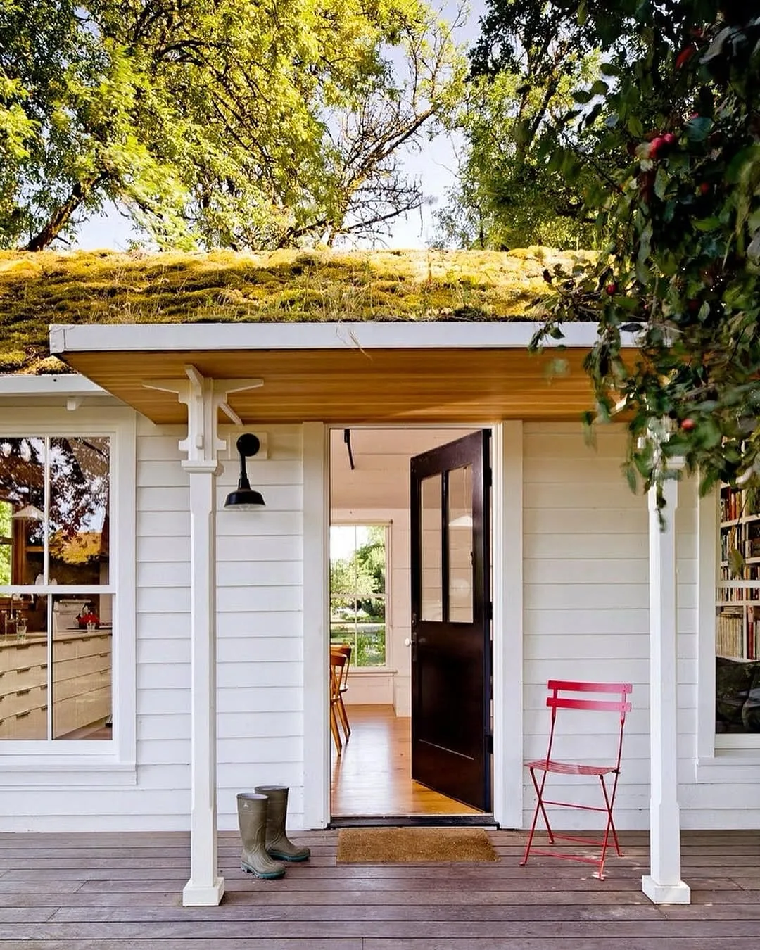 White cottage with a green roof and an open door welcoming visitors