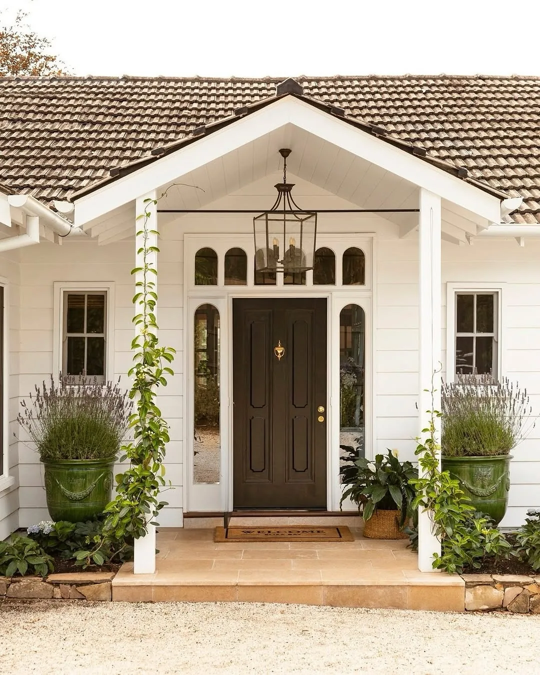 Dark wood front door with a tile roof and planters flanking the entry
