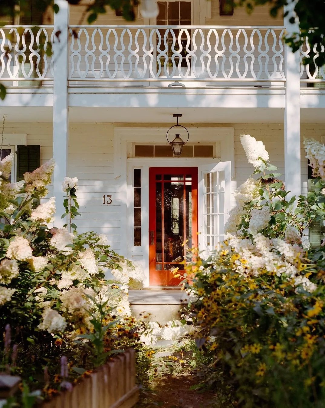 White house with an orange front door framed by hydrangeas