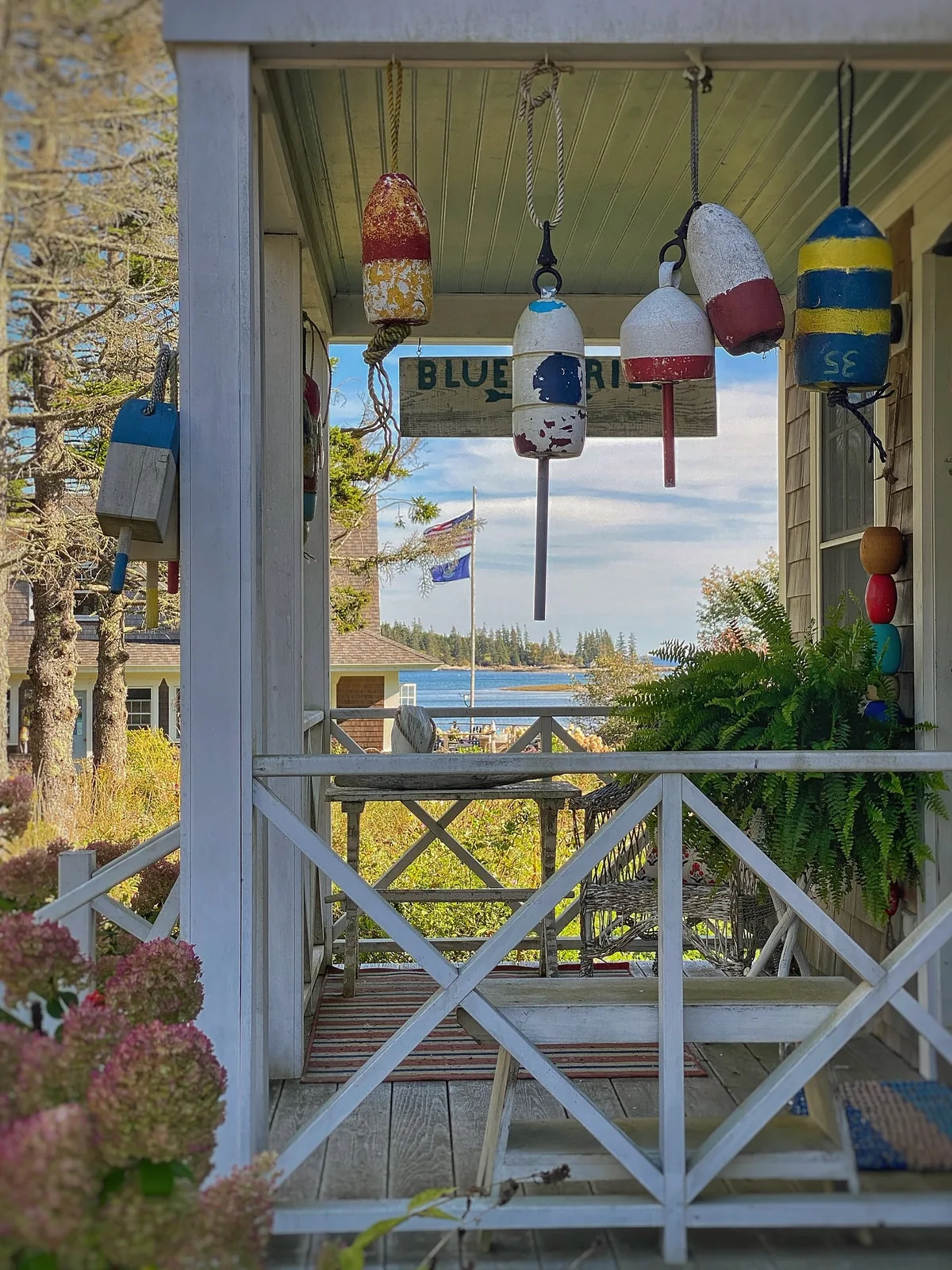 White railing porch with hanging ferns and buoys