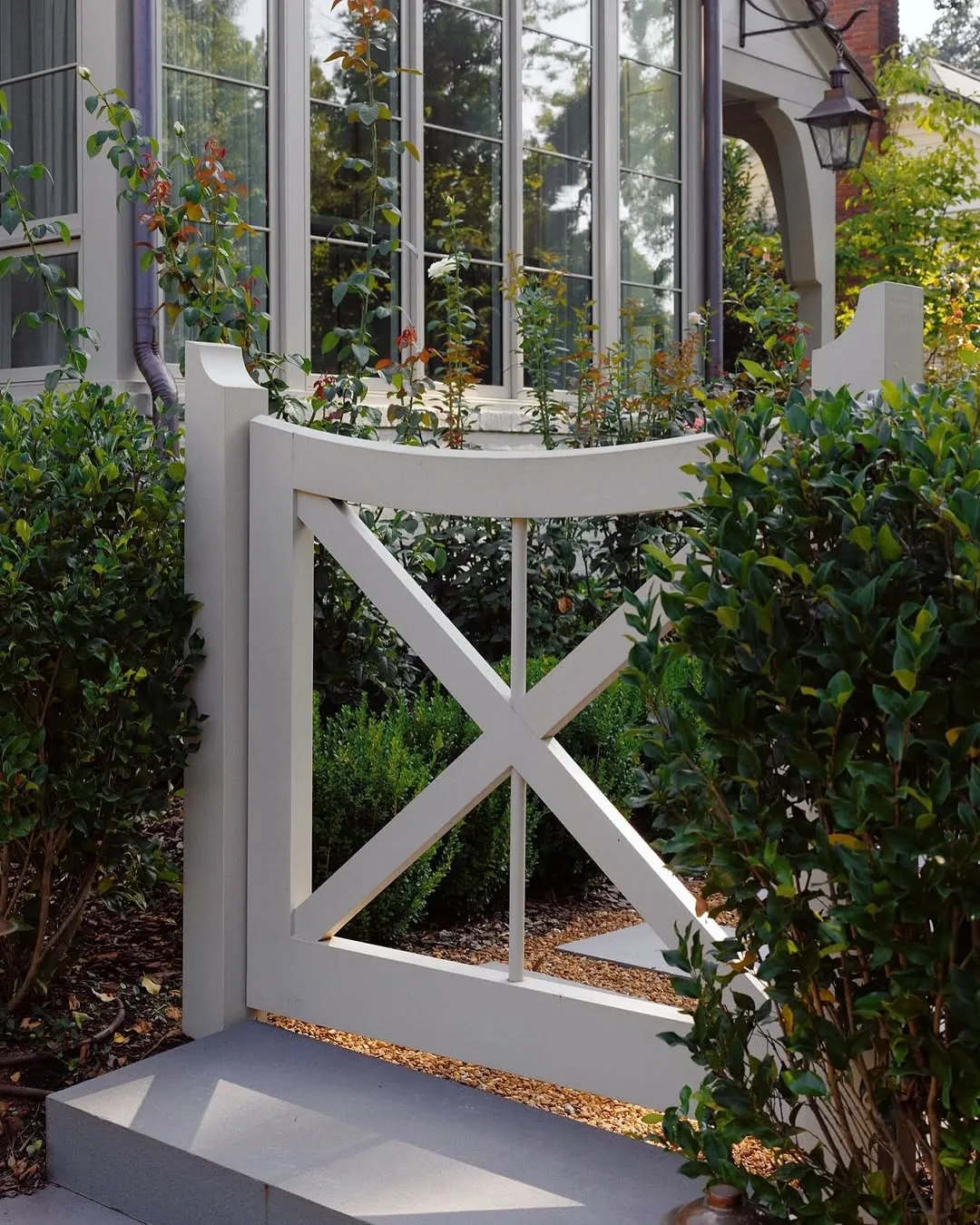 White cross-rail porch with a boxwood hedge defining the edge