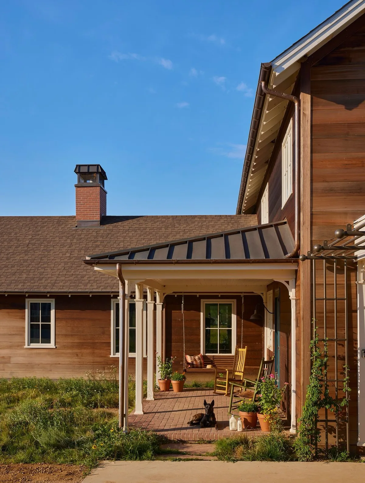 Covered porch of a cedar barn house with rocking chairs