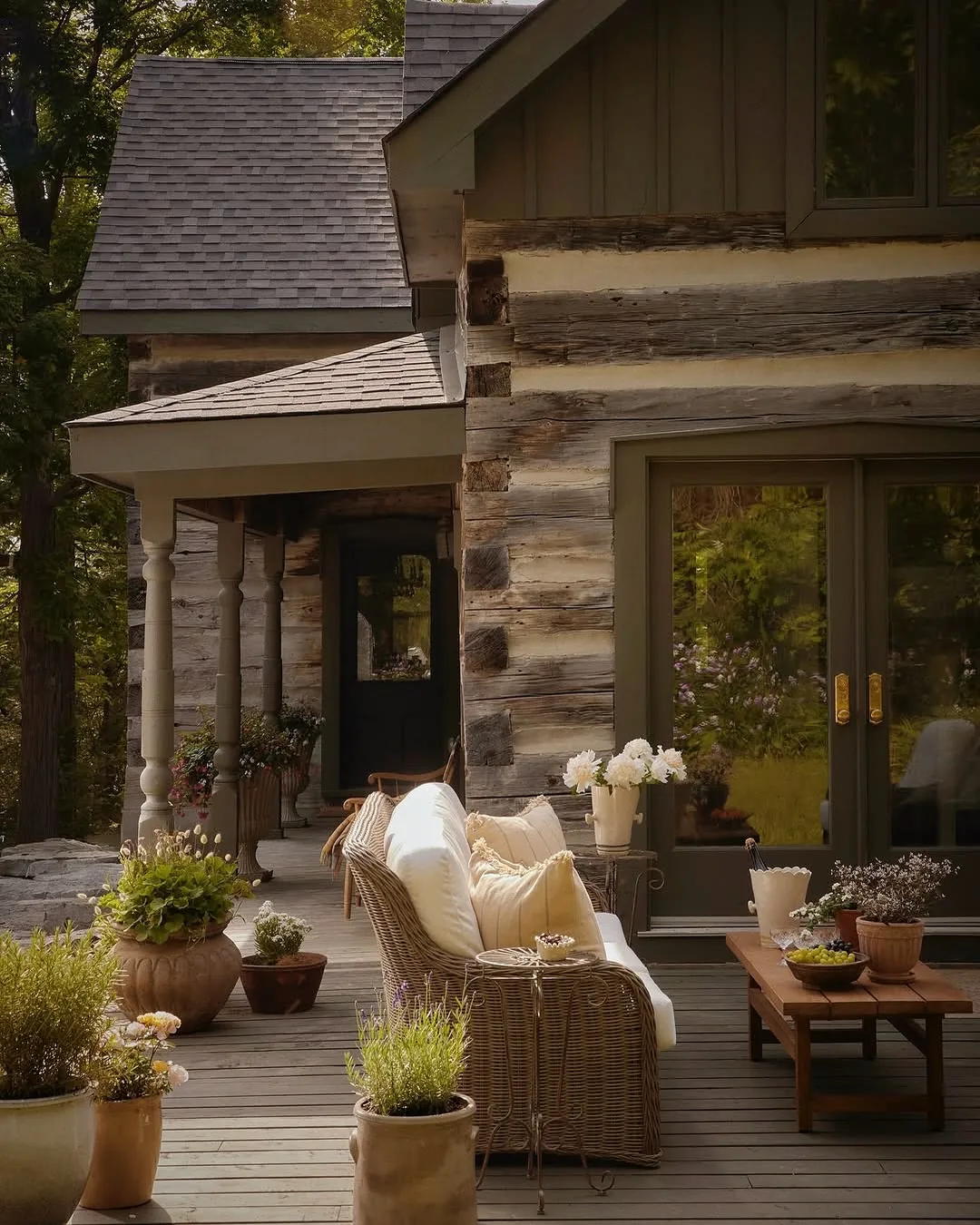 Log cabin porch with wicker seating and planters