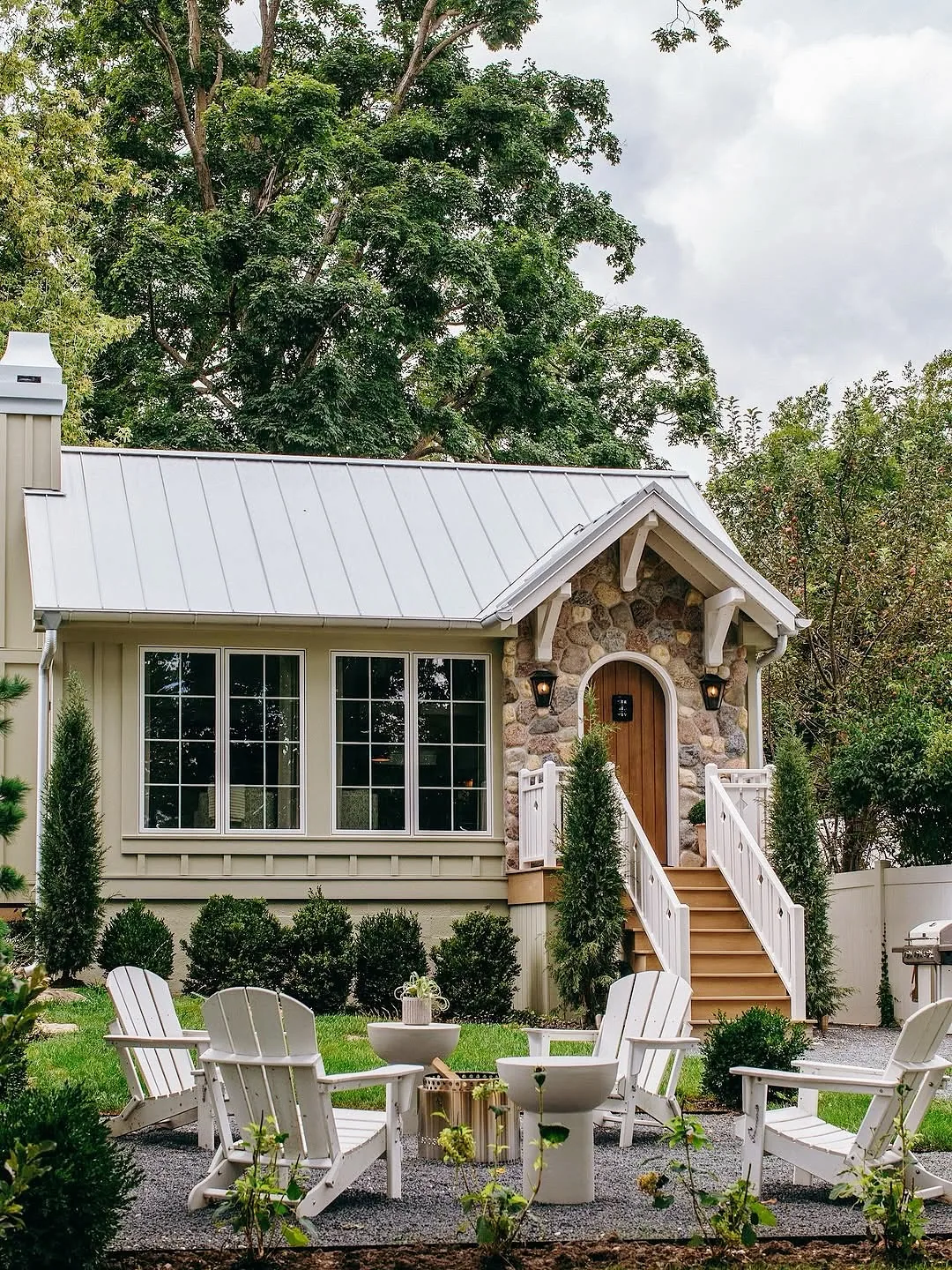 Stone gabled entry with a metal roof and Adirondack chairs