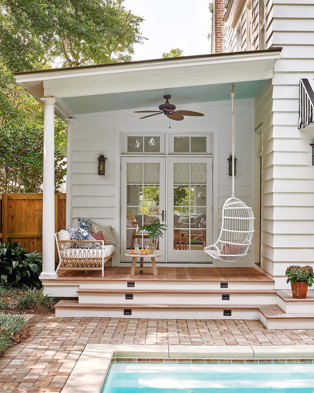 White clapboard porch with a hanging rattan chair