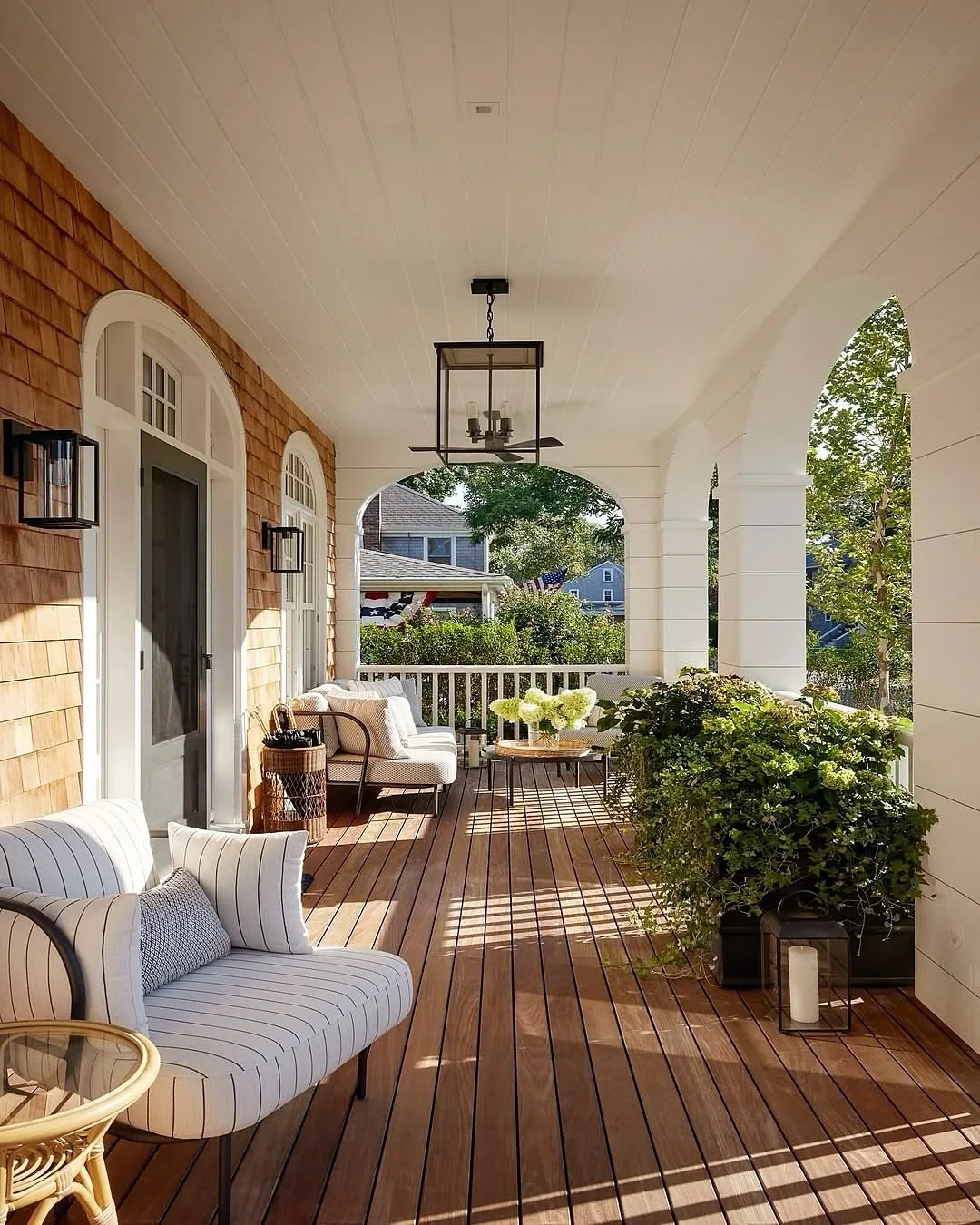 Coastal covered porch with breezy furniture arranged for conversation