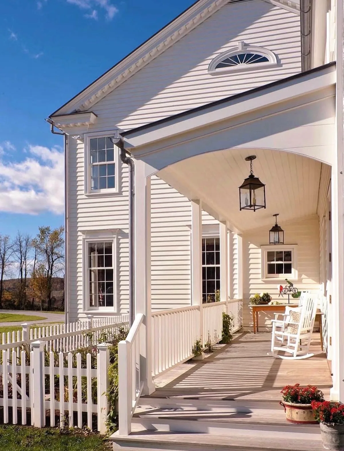 White farmhouse covered front porch with simple seating