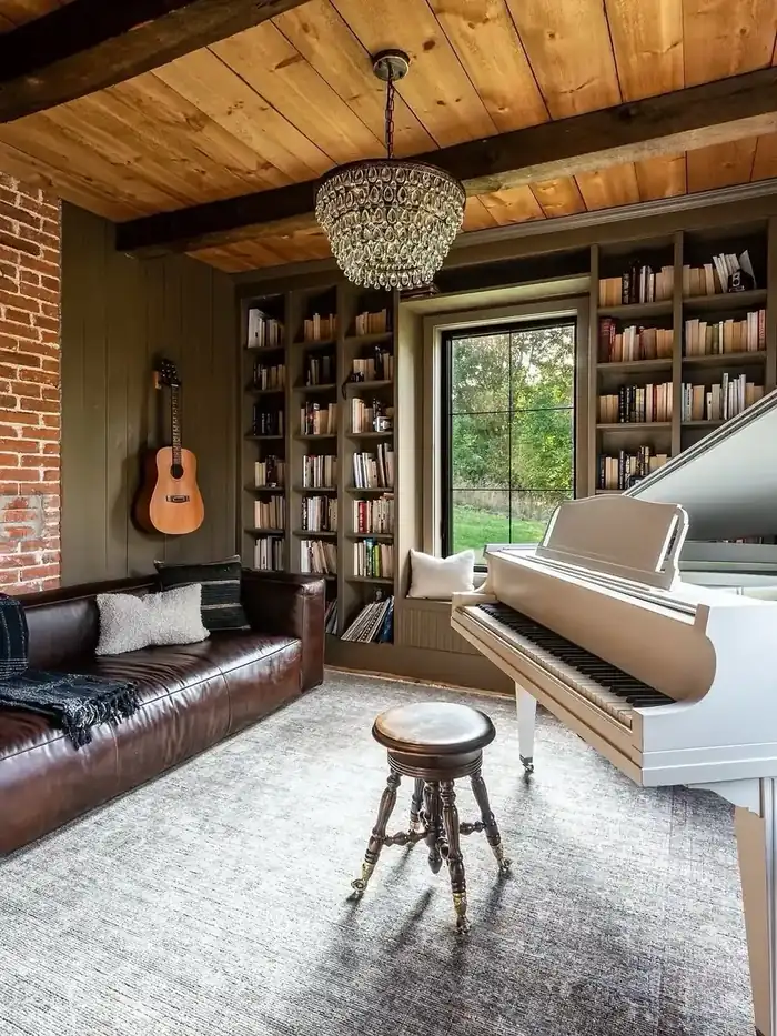 Collected music room with a leather sofa, white grand piano, and floor-to-ceiling bookshelves