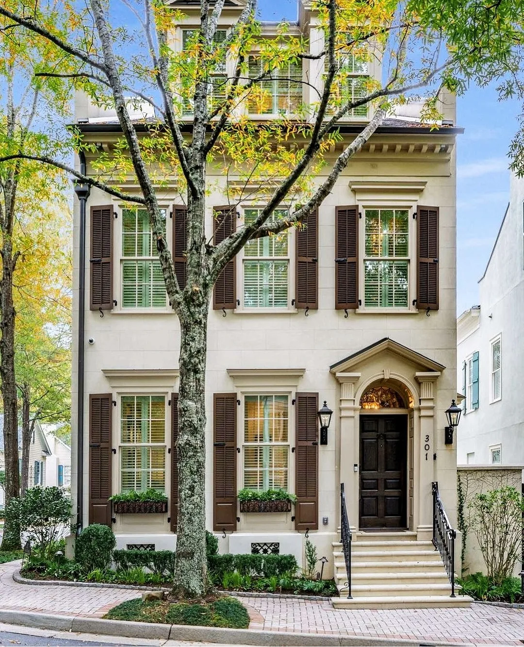 Cream townhouse with brown shutters and an arched door