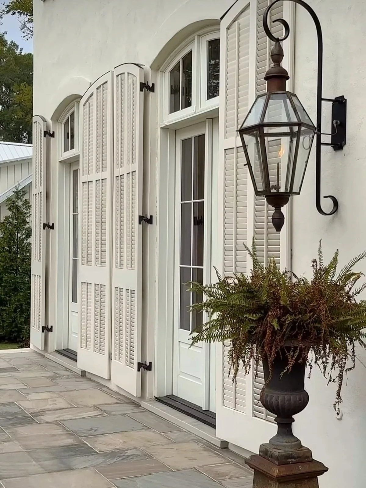 French country exterior with white shutters and a lantern
