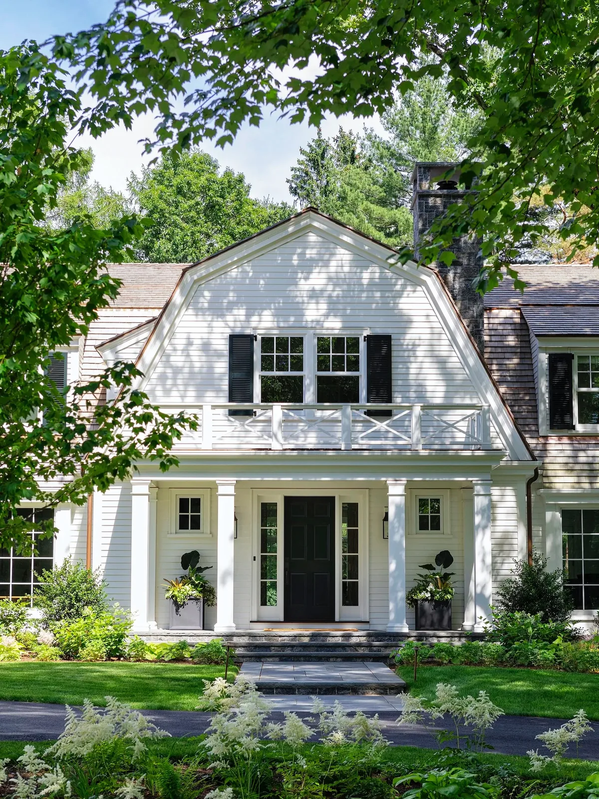 White gambrel house with black shutters and a portico
