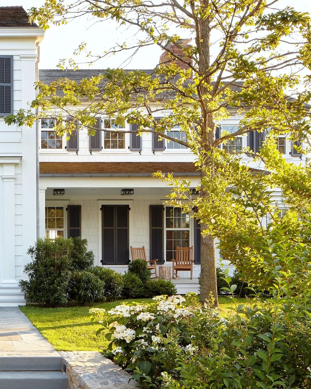 White house with black shutters and a hydrangea border