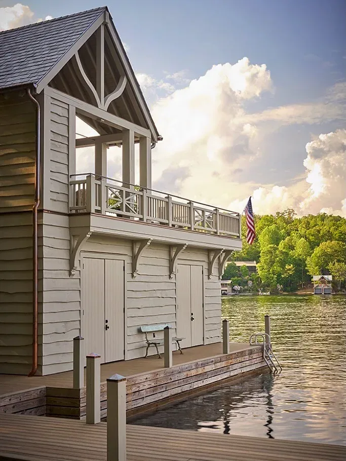 Cream clapboard boathouse with balcony over a dock on the lake