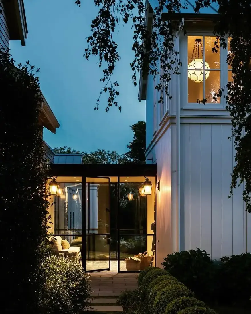 Board and batten house with glass breezeway at dusk with warm interior lights