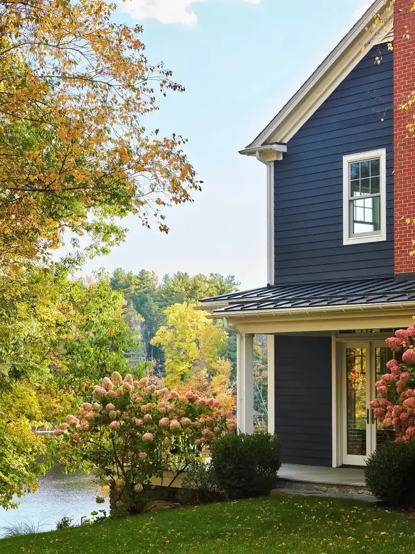 Navy clapboard house with hydrangeas and lake view beyond