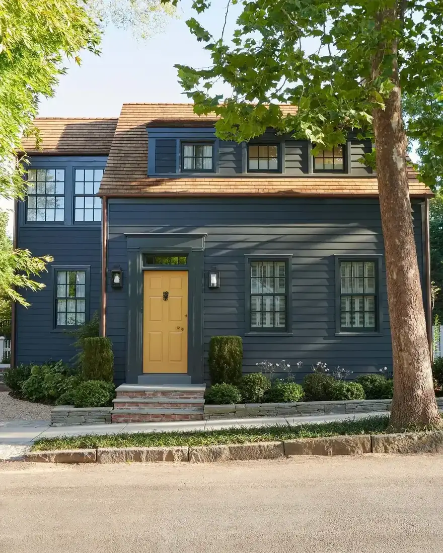 Navy clapboard house with bright yellow front door and white trim