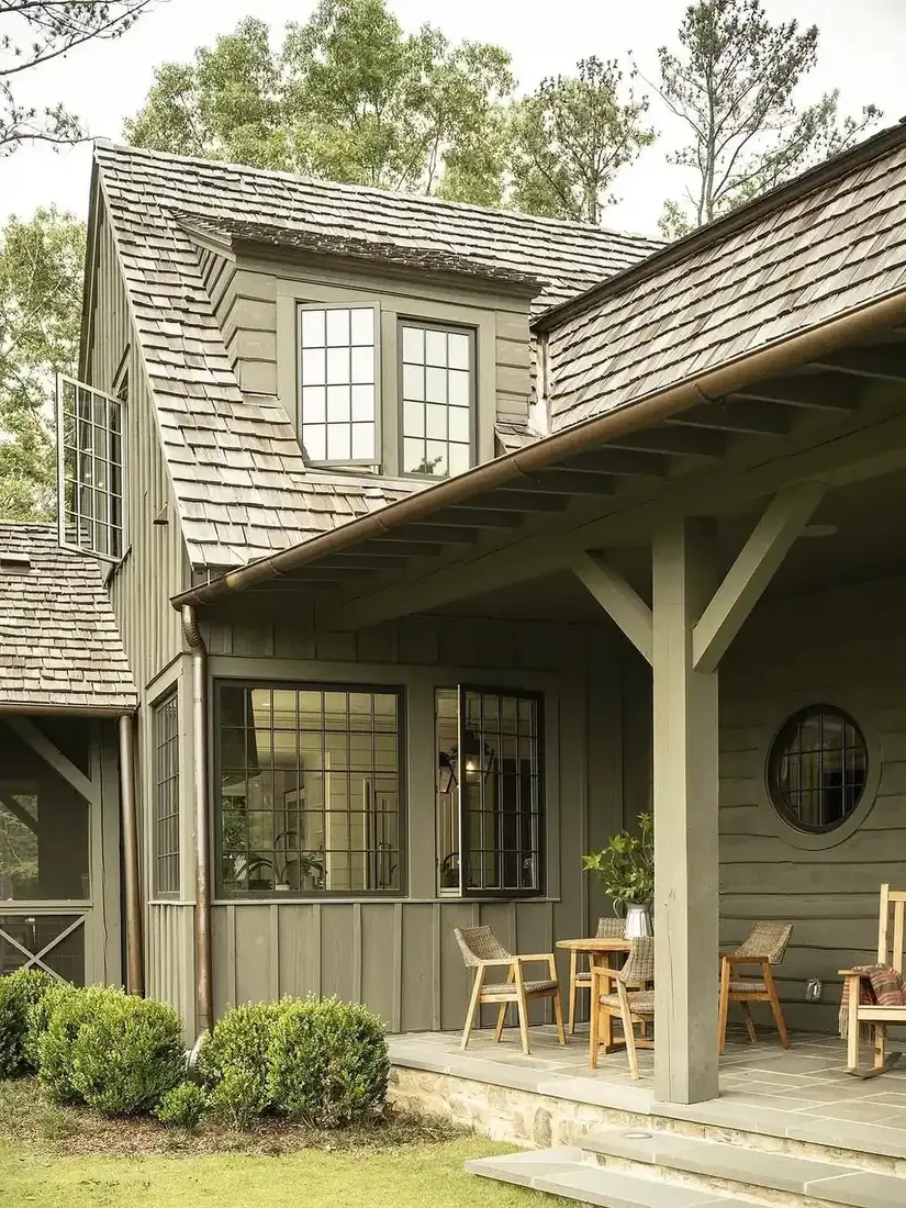 Olive board and batten cottage with covered porch and white trim